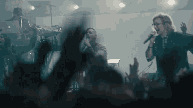 a man singing into a microphone in front of a crowd at a concert