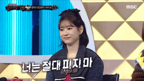 a woman is sitting in front of a mbc sign