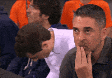 a man covering his mouth with his hand in a crowd of people