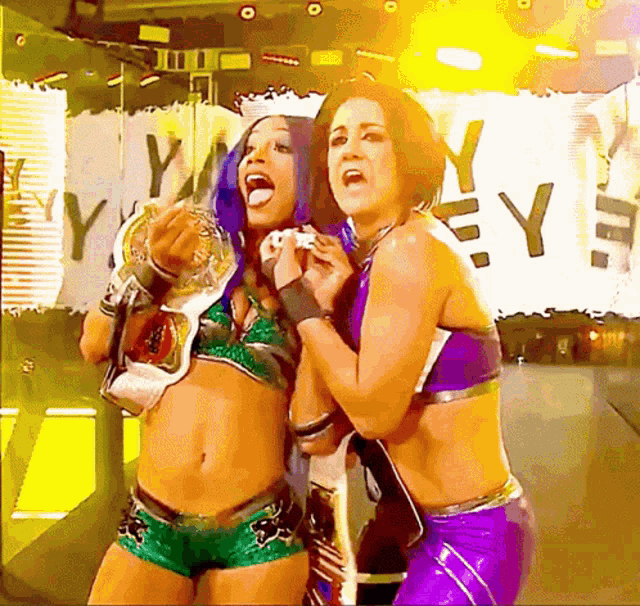 two female wrestlers are standing next to each other in front of a sign that says " y "