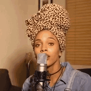 a woman is singing into a microphone wearing a leopard print head scarf .