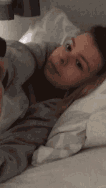 a woman is laying in bed with a blanket on her head