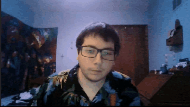 a man wearing glasses and a floral shirt looks at the camera