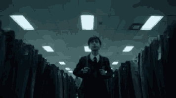 a man in a suit and tie is walking through a store filled with rows of clothes .