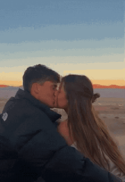 a man and a woman are kissing in front of a desert landscape .