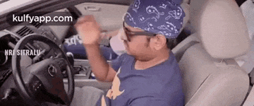 a man is sitting in the driver 's seat of a car wearing a bandana and sunglasses .