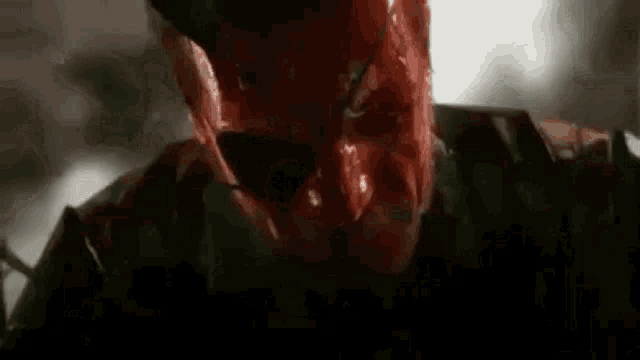 a close up of a man with blood on his face and a red mask .