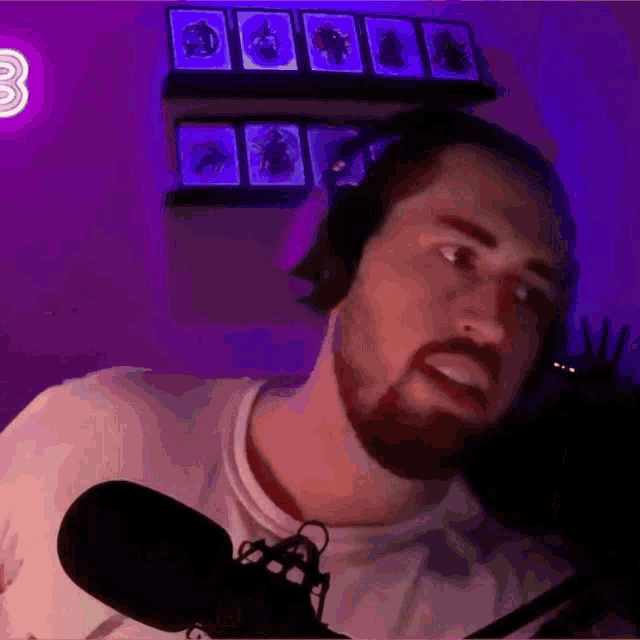 a man with a beard is wearing headphones and a microphone in front of a purple wall with the number 3 on it