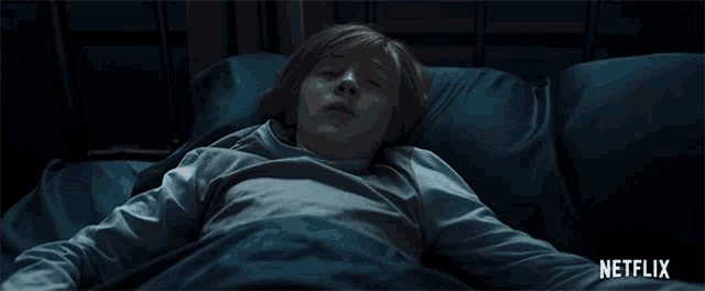 a boy is laying in a bed with a netflix logo on the bottom