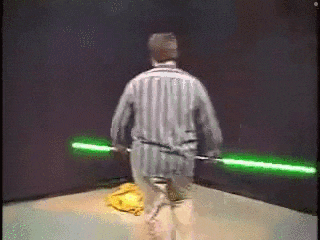 a man in a striped shirt is holding two green lightsabers in his hands .