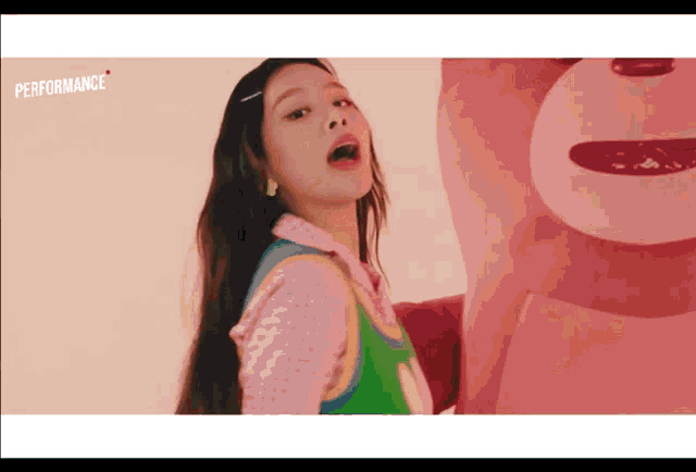 a woman is standing next to a pink teddy bear with the word performance on the bottom right