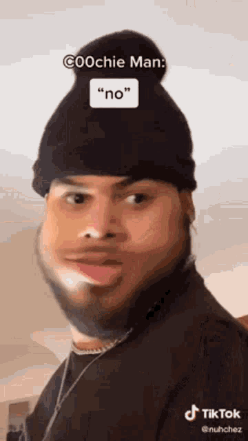 a man with a beard wearing a beanie and a necklace is making a funny face .