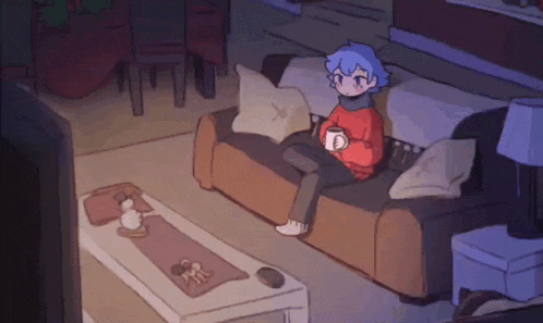a person is sitting on a couch with a cup of coffee and a television .