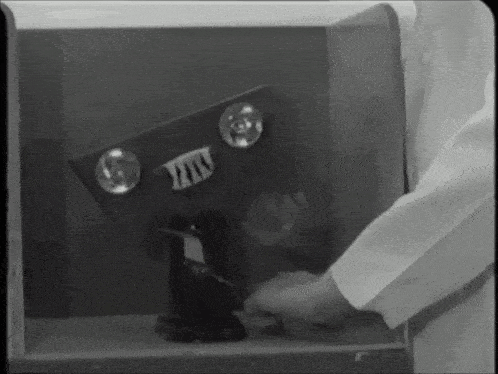 a black and white photo of a person in a lab coat opening a machine