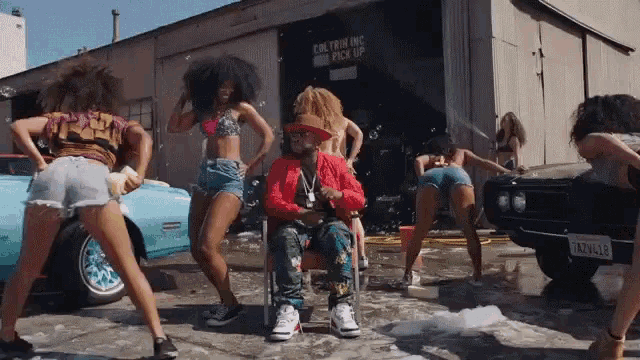 a group of women are dancing in front of a building that says caution while pick up