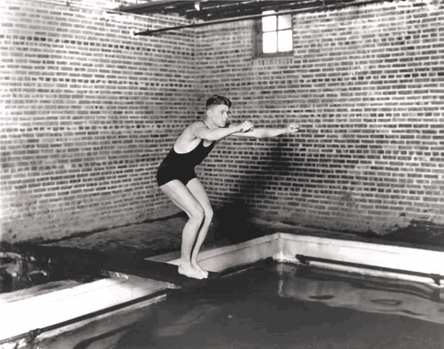 a man in a bathing suit jumps into a pool