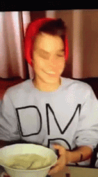 a person wearing a dm sweatshirt holds a bowl of soup