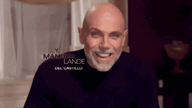 a bald man with a beard is smiling in front of a sign that says manuel landet