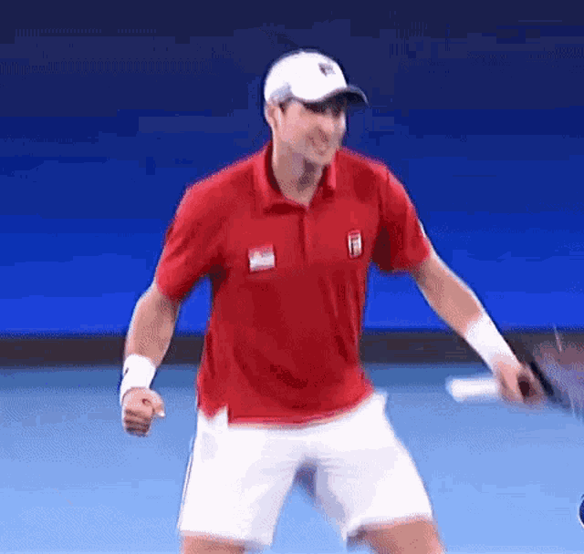 a man in a red shirt and white shorts is holding a tennis racket on a tennis court .