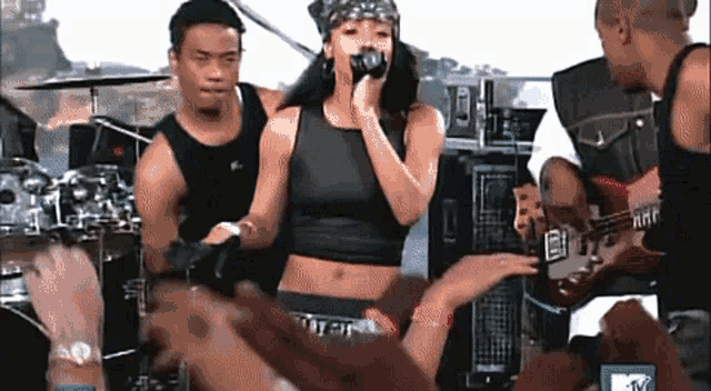 a woman singing into a microphone in front of a crowd with a mtv logo in the corner