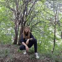 a young girl is squatting in the woods .