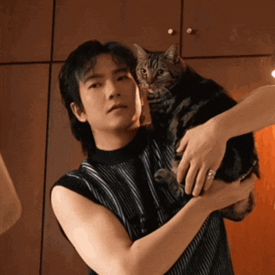 a man holding a cat in his arms with a ring on his finger