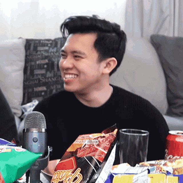 a man sitting on a couch with a bag of jalapeno chips