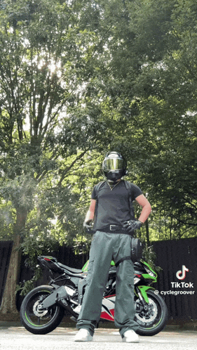 a man wearing a helmet stands in front of a motorcycle with a tiktok watermark on the bottom