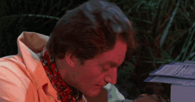 a man with a scarf around his neck is looking down at something