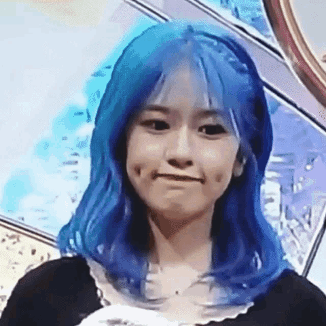 a close up of a girl with blue hair making a face .