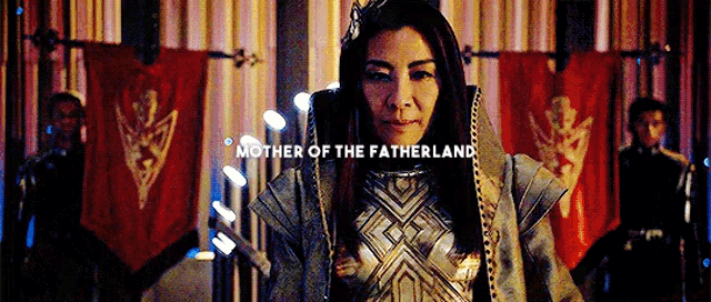 a woman wearing a crown and armor is standing in front of a crowd .