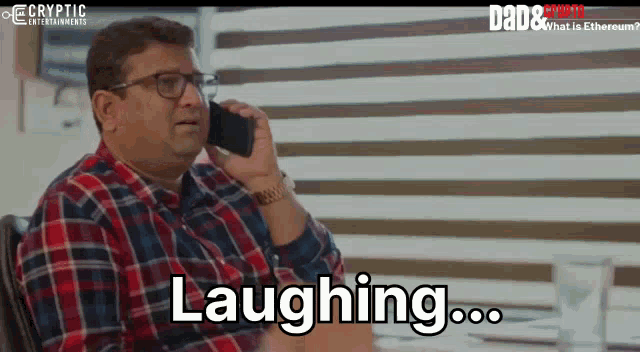 a man in a plaid shirt is laughing while talking on a phone
