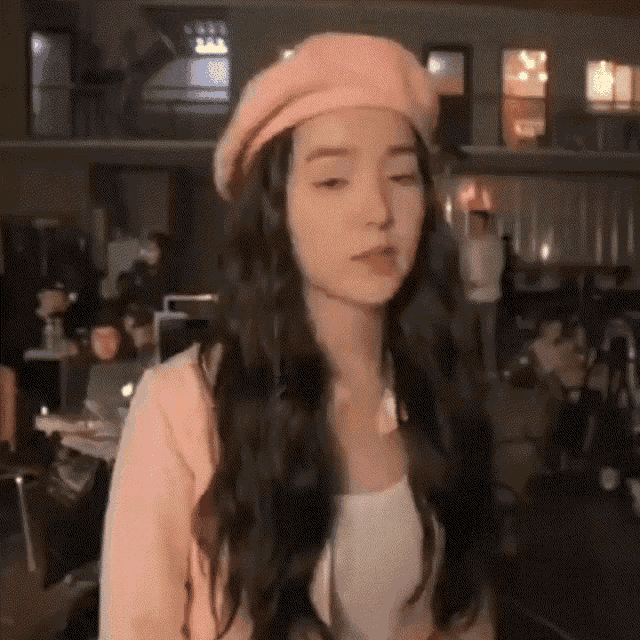 a woman wearing a pink beret and a pink jacket is standing in a room .