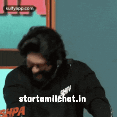 a man wearing a mask and sunglasses is standing in front of a microphone and says starttamilchat.in