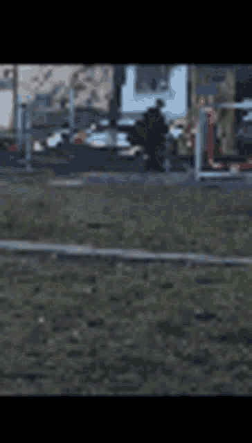 a blurry picture of a park with a fence and a few buildings in the background