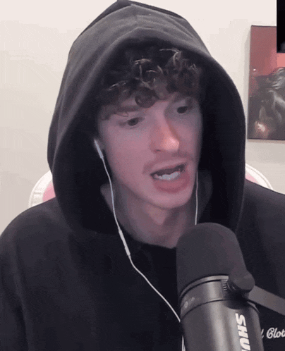 a man wearing headphones and a shure microphone looks at the camera
