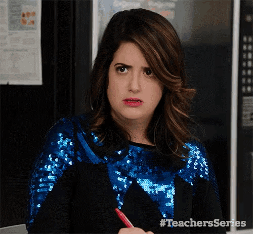 a woman in a blue sequined top is holding a red pen and making a funny face .