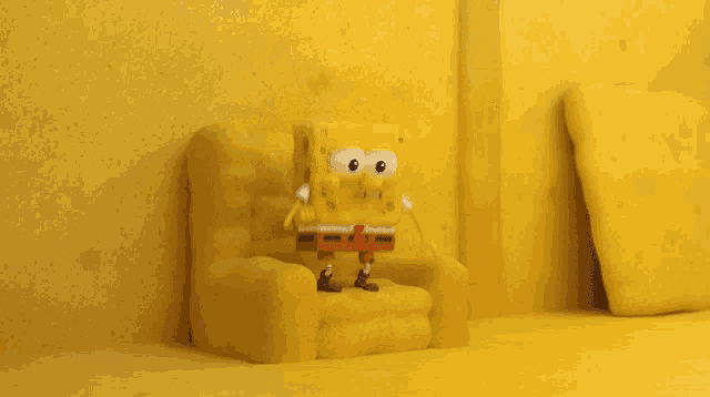 spongebob squarepants is sitting in a yellow chair with his arms outstretched