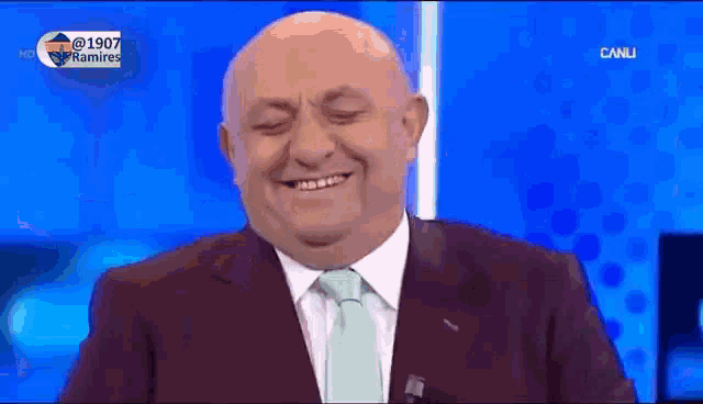 a man in a suit and tie is smiling on a blue background