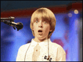 a young boy singing into a microphone with a surprised expression on his face