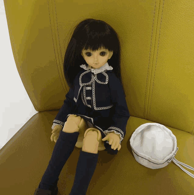 a doll is sitting on a yellow chair next to a white purse