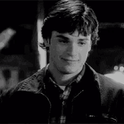 a black and white photo of a young man wearing a plaid shirt and a jacket .