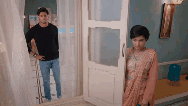 a man and woman are standing in a room with a door open