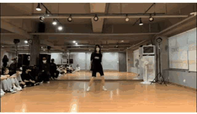 a woman is dancing in front of a large mirror in a dance studio ..