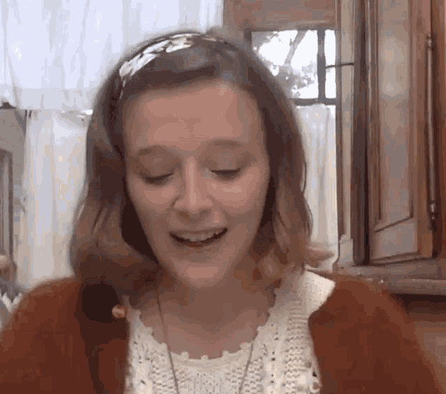 a woman wearing a headband and a sweater smiles