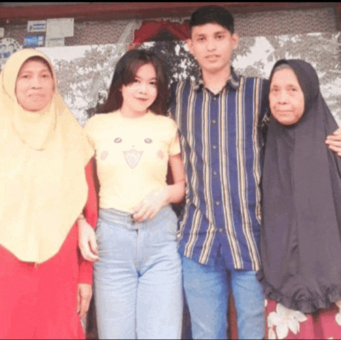a group of people posing for a picture including an older woman wearing a black hijab