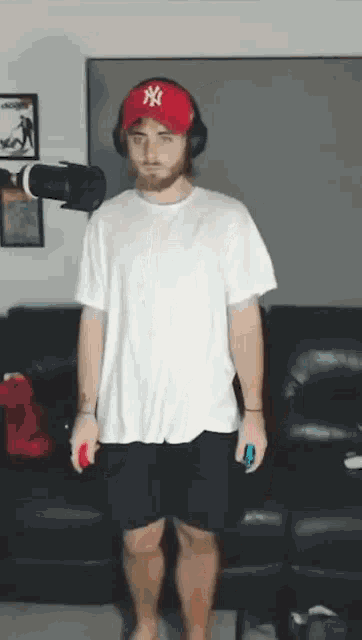 a man wearing headphones and a ny hat is standing in front of a couch