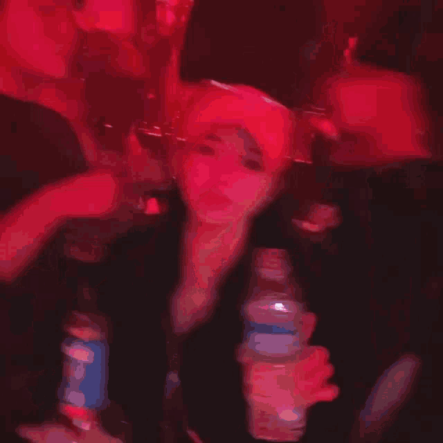 a person holding a bottle of pepsi in a red light