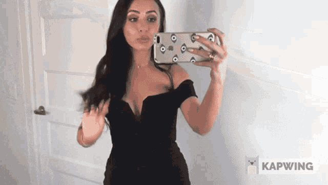 a woman in a black dress is taking a picture of herself
