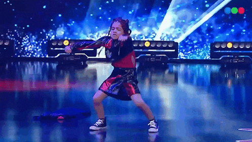 a young girl is dancing on a stage in front of a blue light